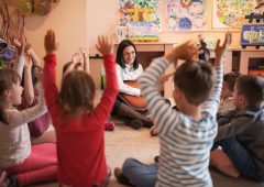 Smiling female teacher playing a guitar during music class in a preschool.