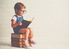 happy child little girl with glasses reading a books